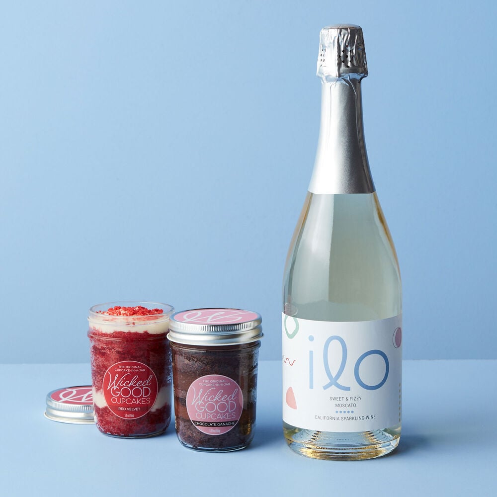 This gift features Wicked Good Cupcakes Chocolate Ganache and Red Velvet Cupcake Jars paired with Ilo Moscato California Sparkling Wine. image number null