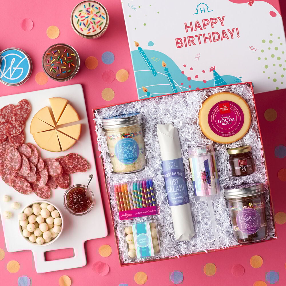 This birthday gift includes cupcakes, Classico Dry Salami, Smoked Gouda Blend, Strawberry Fig Jam, and Confetti Cake Bites, birthday candles, and a confetti popper. image number null